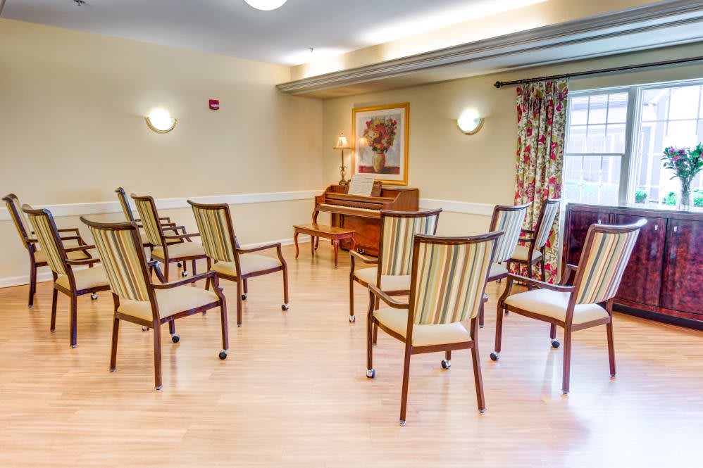 A well-lit room with chairs arranged in a circle on a wooden floor, suitable for meetings or group activities.