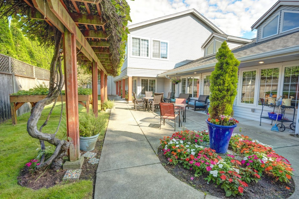 A beautiful garden patio with outdoor seating and vibrant plants surrounding a modern building.