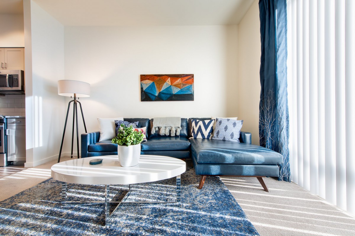 A modern living room with a blue sofa, abstract artwork, and a round coffee table.