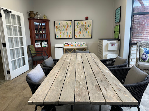 A cozy meeting room featuring a large wooden table, comfortable chairs, and colorful artwork on the walls.