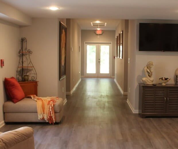 A modern living room with a hallway leading to double doors, featuring contemporary decor and wood flooring.