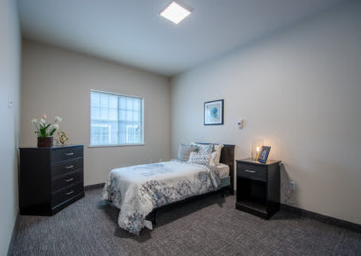 A minimalist bedroom with a single bed, nightstand, and dresser.
