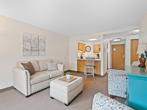 A modern apartment living room with a comfortable sofa and an adjoining kitchen area.