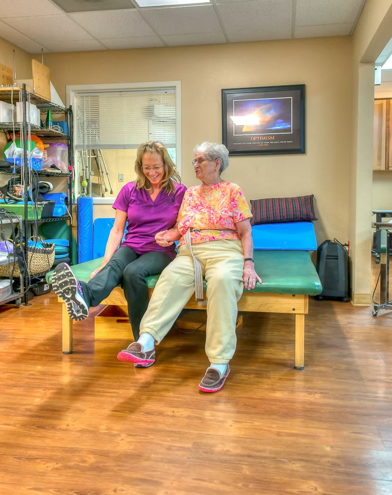 Two women share a joyful moment during a physical therapy session.