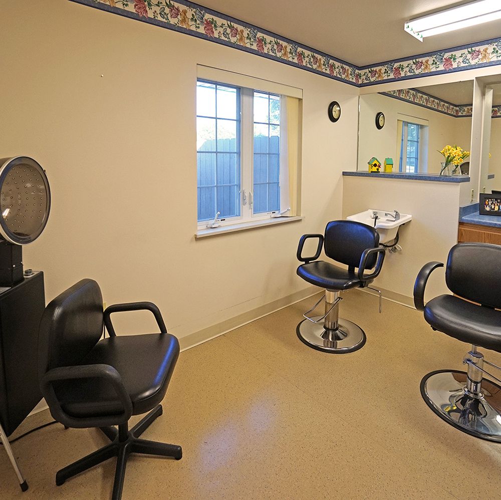 An interior view of a hair salon with styling chairs and a mirror.