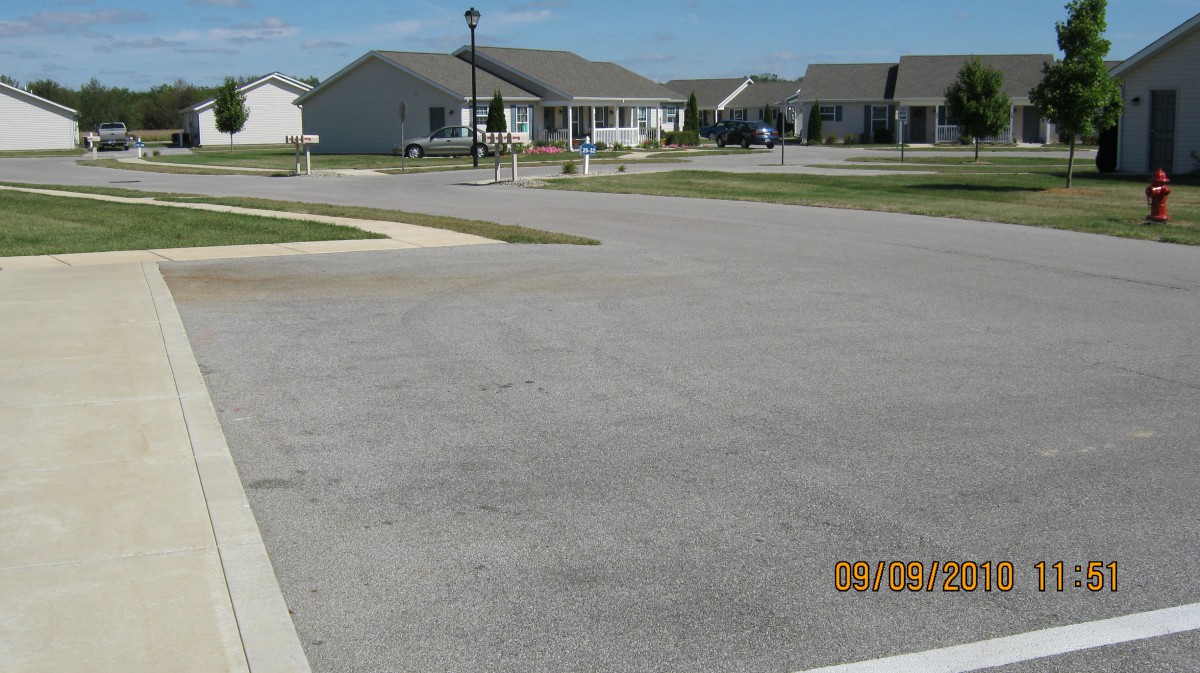 A quiet suburban neighborhood with houses and a street under a clear blue sky.
