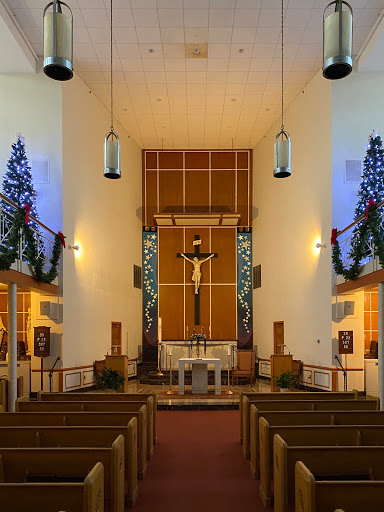 A beautifully decorated church interior, showcasing a central altar with a cross and festive Christmas decorations.