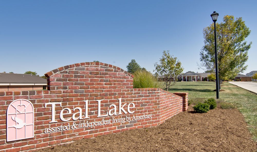 Brick sign for Teal Lake subdivision against a clear blue sky.