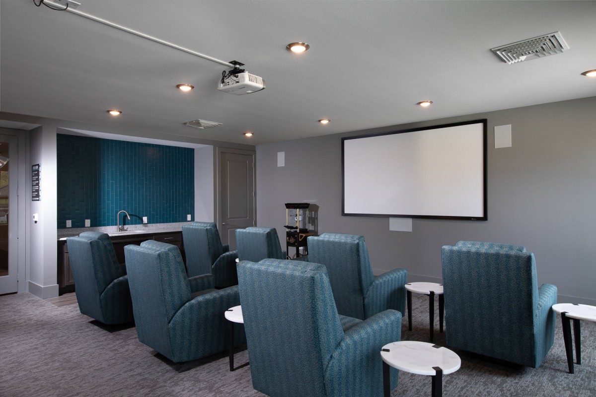 A cozy home theater room with multiple comfortable chairs facing a large projector screen.