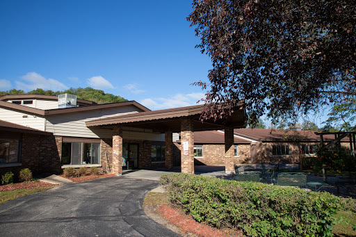 A scenic view of a modern building with stone accents, surrounded by greenery and under a clear blue sky.