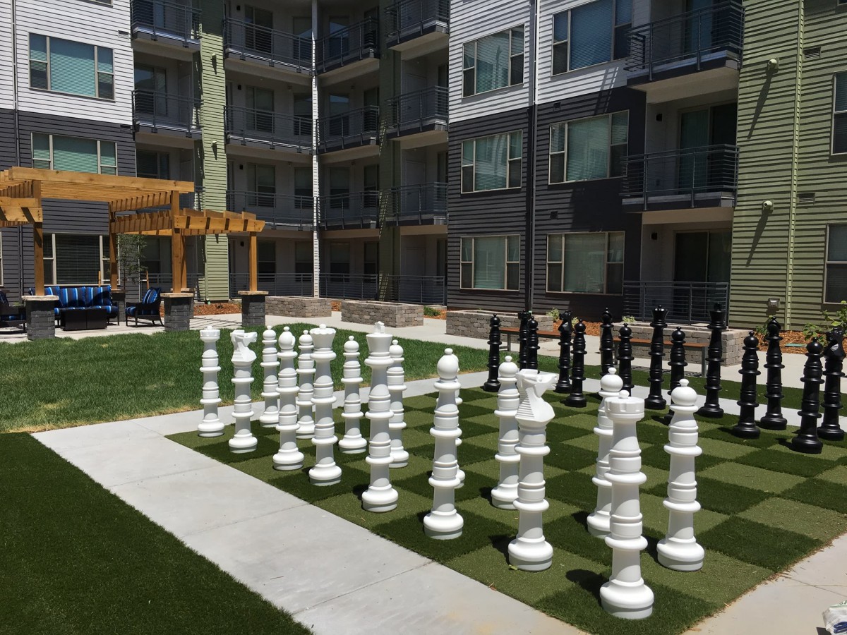 A large outdoor chess set on a grassy lawn in an apartment complex courtyard.