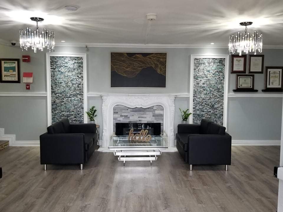 A modern living room with a fireplace, black chairs, and elegant chandeliers.