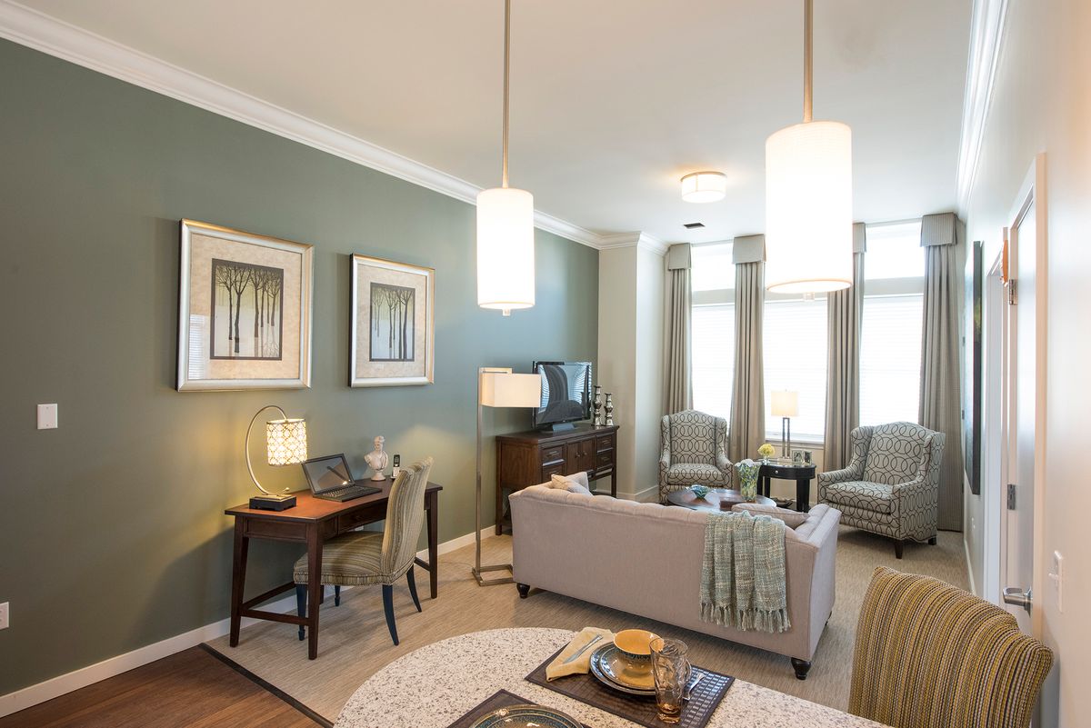 A modern apartment living room featuring a comfortable sofa, artwork on the walls, and elegant lighting.