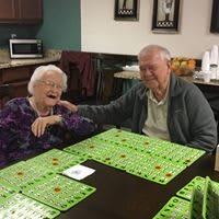 Two seniors enjoying a game of bingo at a table.