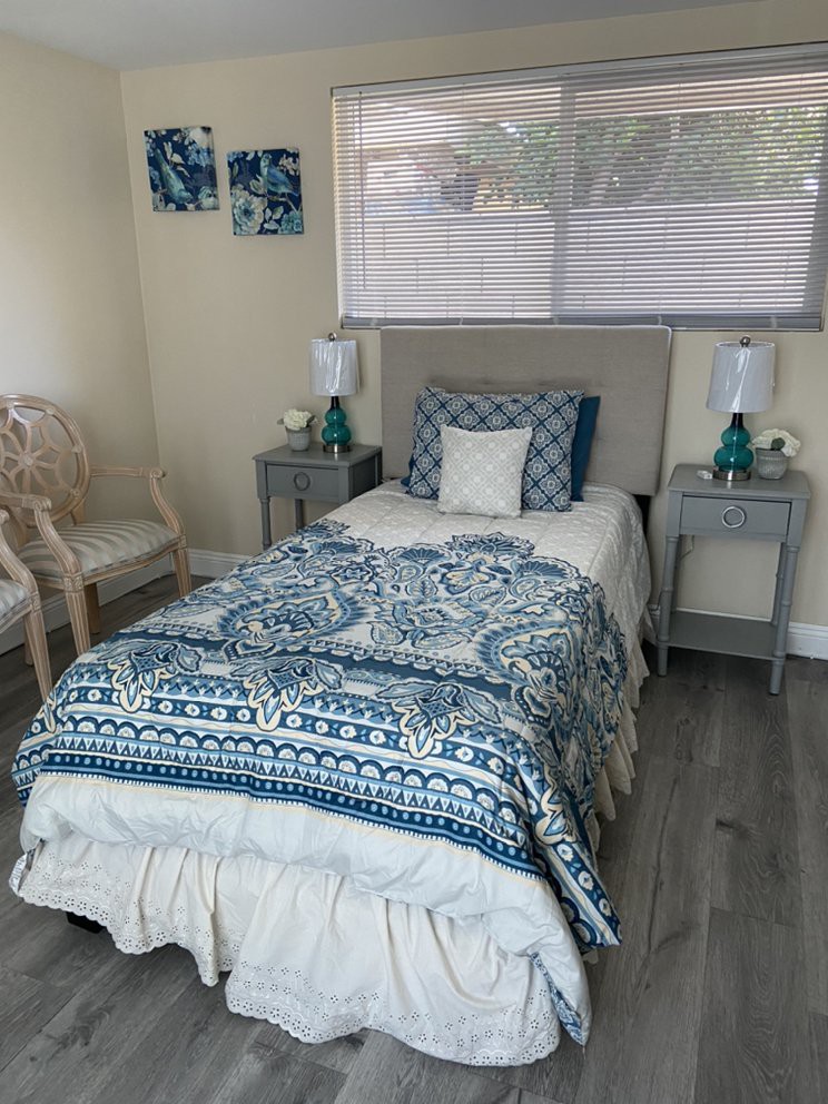 A cozy bedroom with a single bed, decorative pillows, and matching nightstands with lamps.
