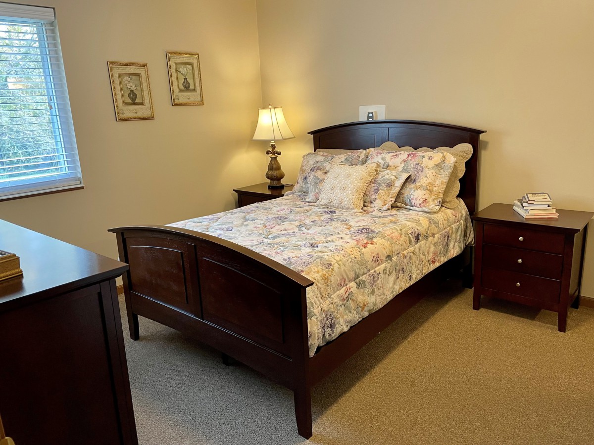 A cozy bedroom with a wooden bed frame, floral bedding, and matching nightstands and lamps.
