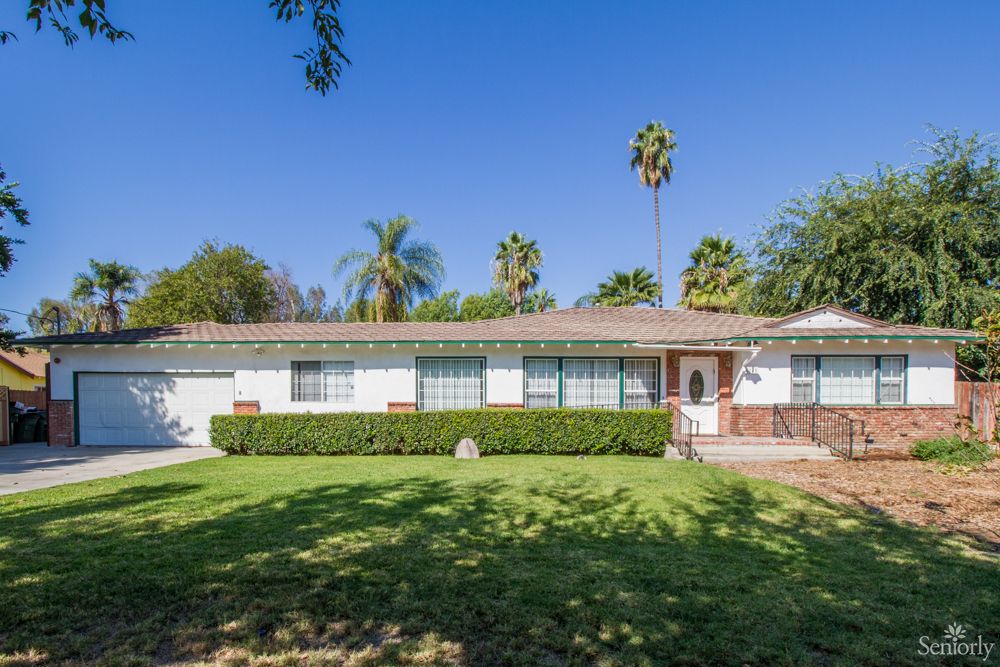 A single-story house with a well-maintained front yard and palm trees.
