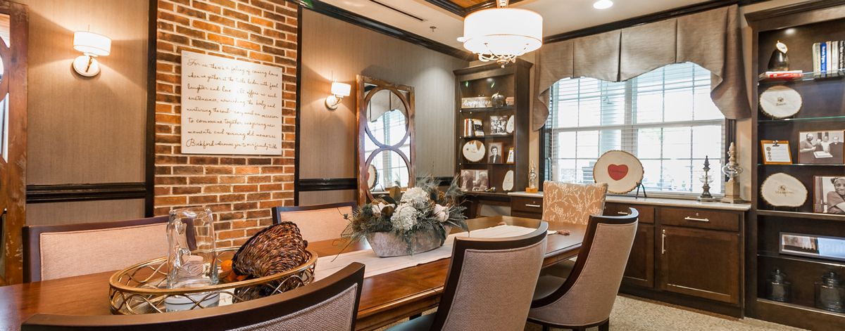 A cozy dining room featuring elegant decor, a chandelier, and a wooden table surrounded by comfortable chairs.