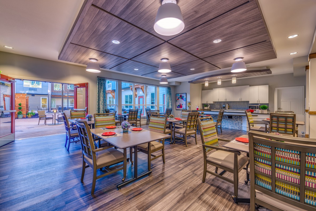 A modern and spacious dining area with neatly arranged tables and chairs, featuring stylish lighting and a wooden floor.
