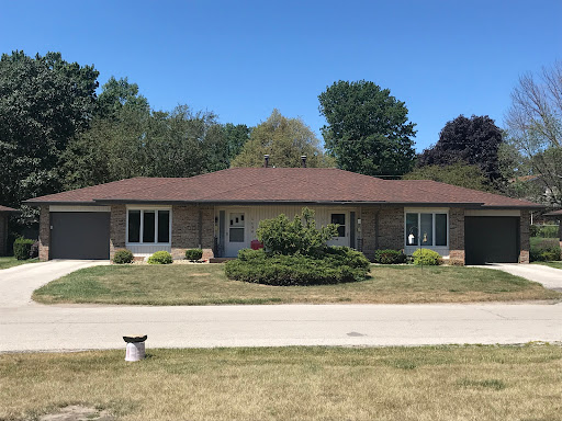 A charming single-story house with a well-maintained lawn under a clear blue sky.