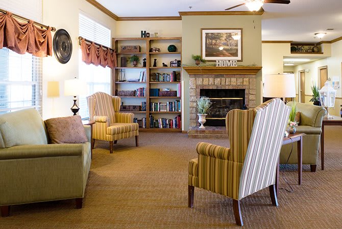 A cozy living room with armchairs, a fireplace, and a bookshelf.