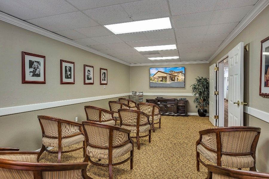 An interior view of a waiting room with arranged chairs and framed pictures on the walls.