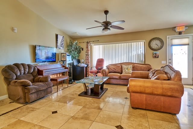 A cozy living room with comfortable seating, a television, and a ceiling fan.