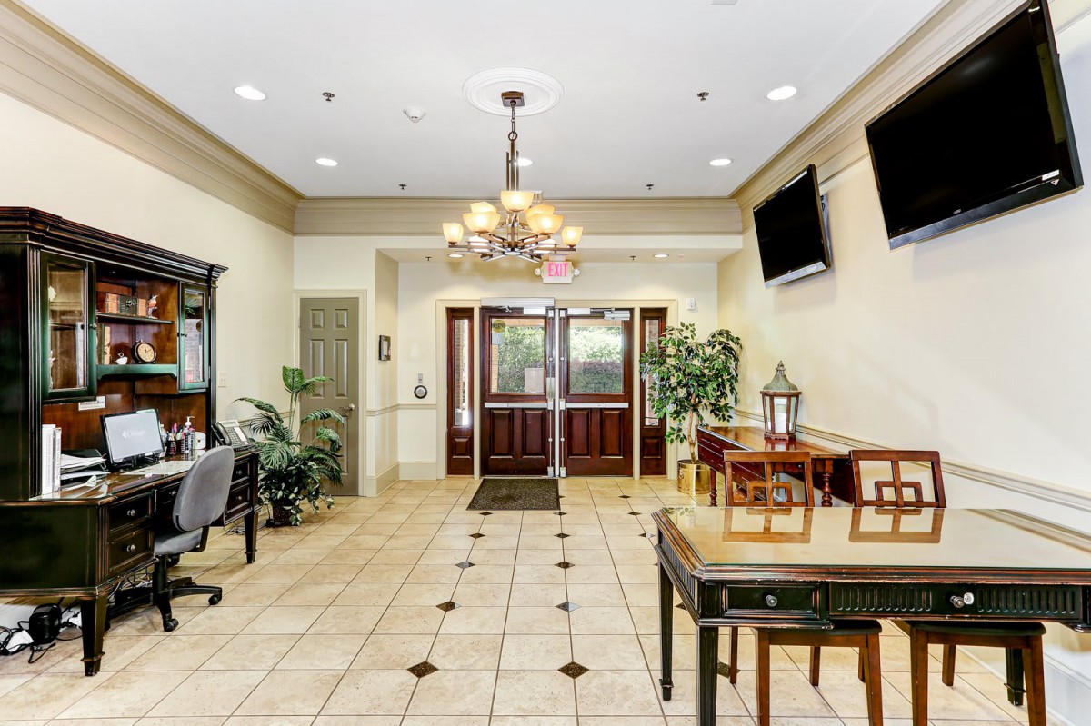 A well-lit lobby area featuring seating, a chandelier, and decorative plants.