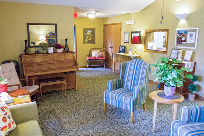A cozy living room featuring a piano, striped armchair, and various home decor elements.