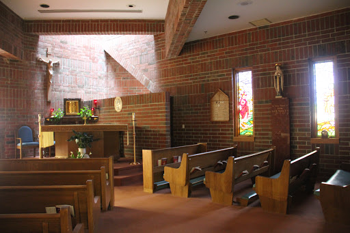 The serene interior of a brick church, featuring wooden pews and an altar bathed in natural light.