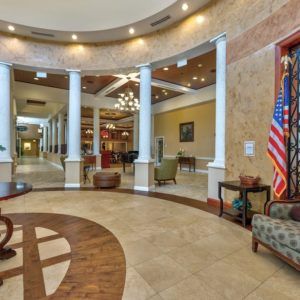 A spacious and elegantly designed lobby with white columns, comfortable seating, and an American flag.