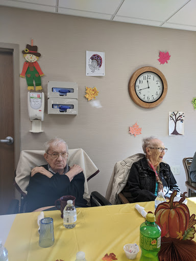 A cozy gathering of elderly residents in an assisted living facility, surrounded by seasonal decorations.