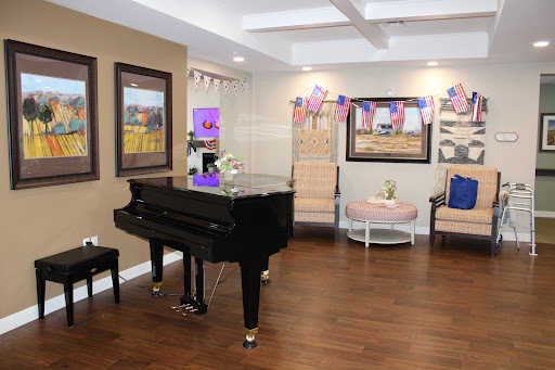 A cozy lounge area featuring a black piano, elegant seating, and decorative artwork.