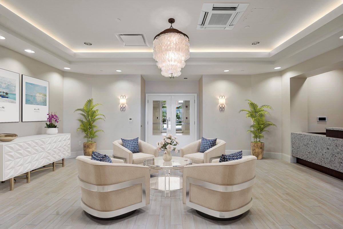 A modern lounge area with plush seating, elegant chandelier, and decorative plants.