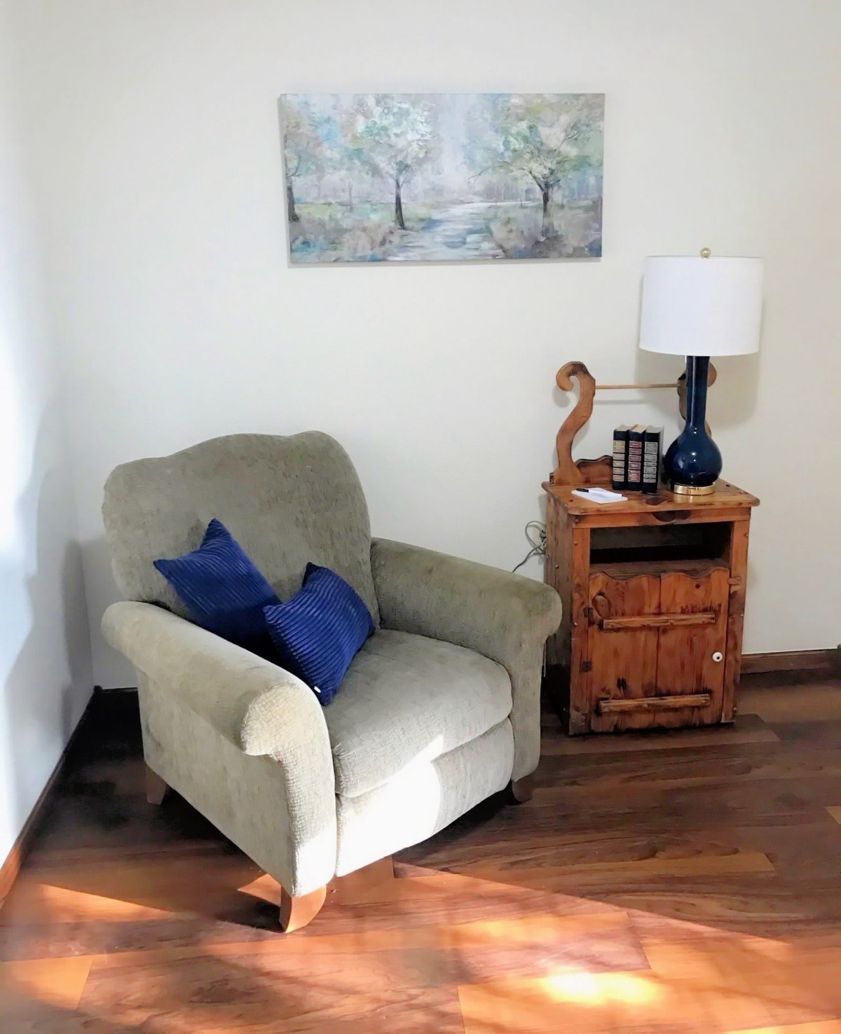 A cozy corner with an armchair, side table, and lamp in a warmly lit living room.