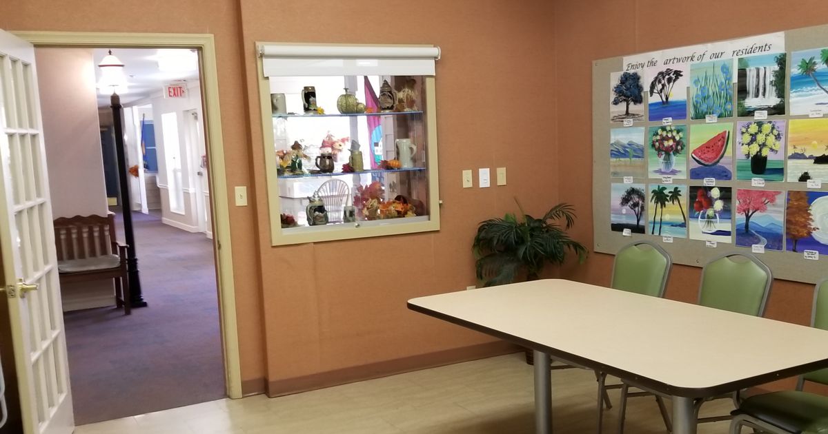 A room with a display case filled with decorations, a table, and a plant.