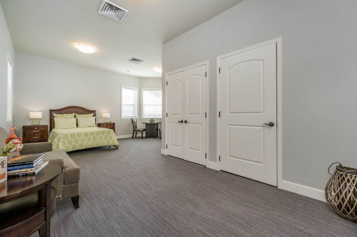 A spacious and modern bedroom with a cozy bed, carpeted flooring, and ample closet space.
