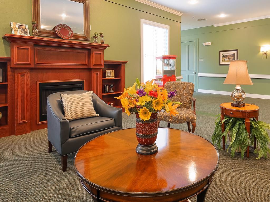 A cozy living room with a fireplace, featuring comfortable seating and a vase of vibrant flowers on the table.