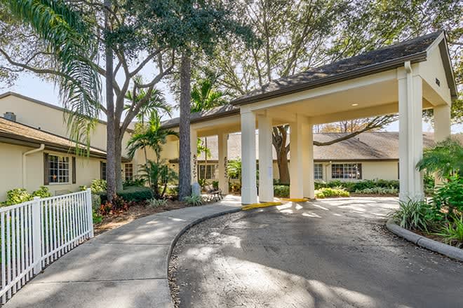 A residential building with a covered entrance and surrounding trees.
