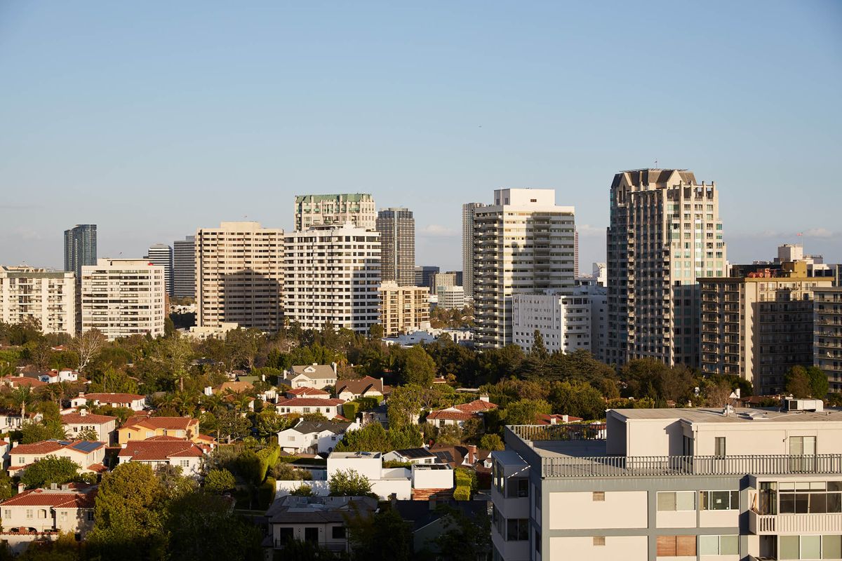 A city skyline featuring a mix of modern skyscrapers and residential buildings under a clear sky.