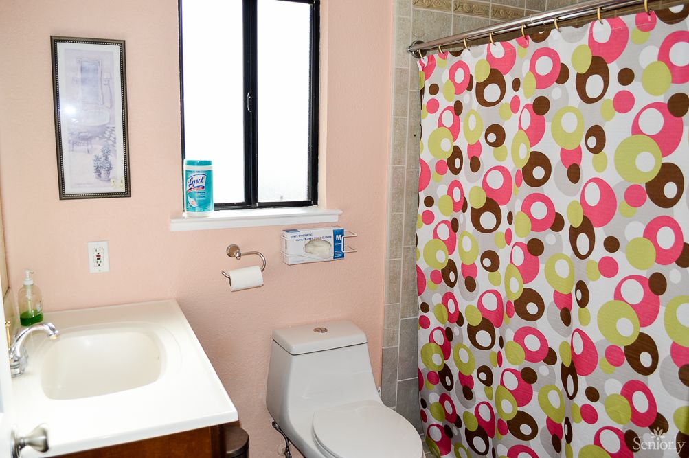 A bathroom featuring a toilet, sink, and a colorful shower curtain with circular patterns.