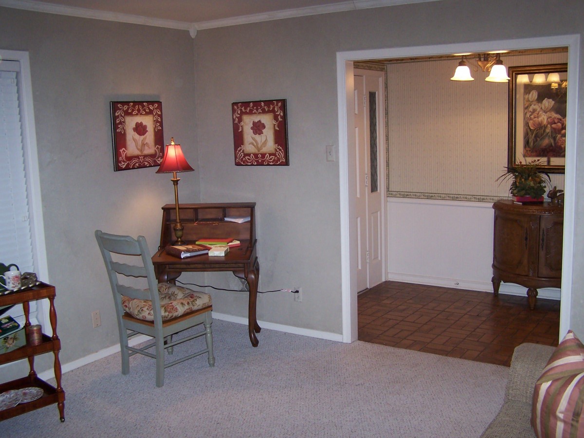 Cozy living room corner with a small wooden desk, chair, and decorative wall art.