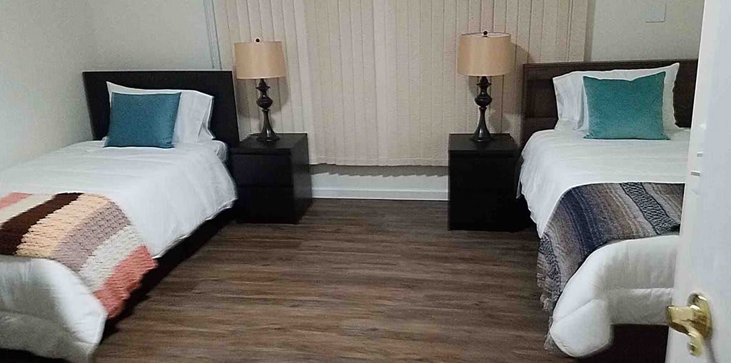 A neatly arranged bedroom with two beds and matching nightstands.