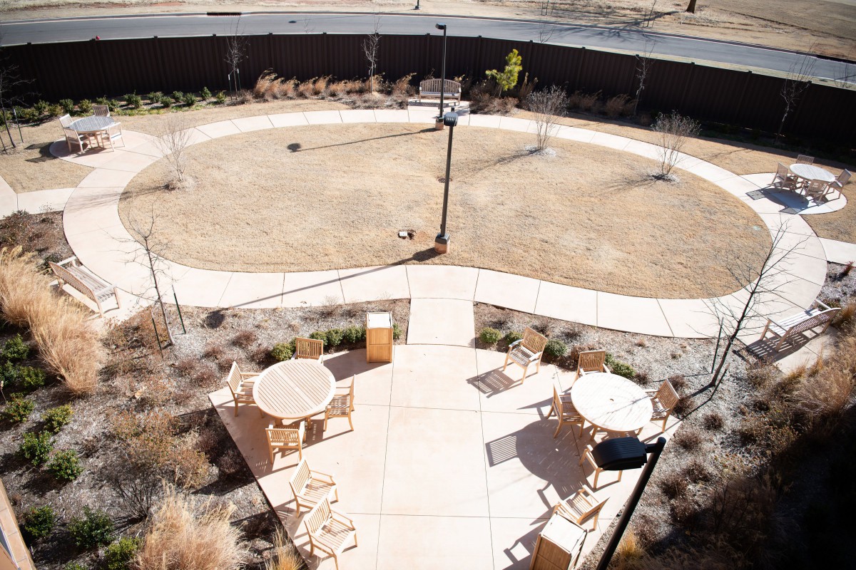 An aerial view of a courtyard featuring outdoor seating with tables and chairs arranged on a paved patio area.