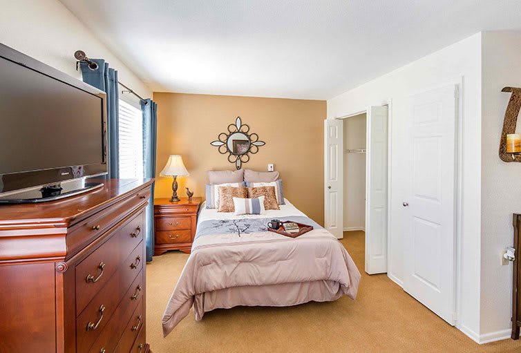 A cozy bedroom featuring a neatly made bed and classic wooden furniture with warm lighting.