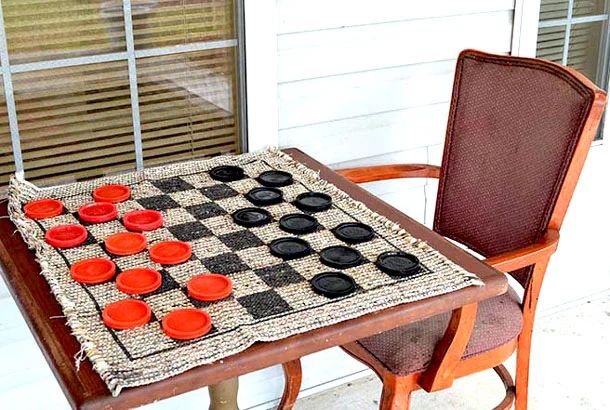 A checkers game set up on a porch table with red and black pieces.