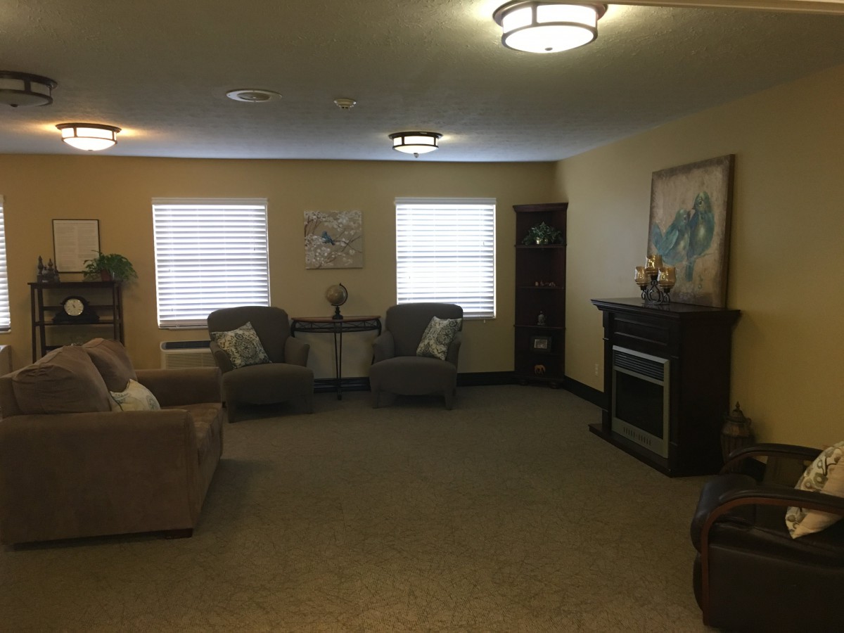 A cozy living room with comfortable seating, a fireplace, and artwork on the wall.