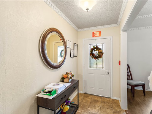 A welcoming entrance featuring a mirror, a decorative wreath on the door, and a console table with various items.
