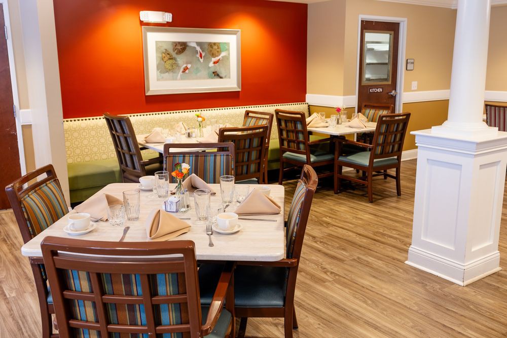 A cozy restaurant dining area with neatly set tables and chairs, featuring warm lighting and elegant decor.