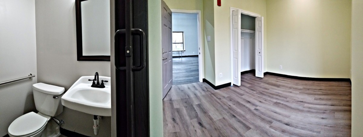 An interior view of an empty room with wood flooring, featuring a closet and a window.